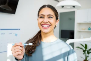 A smiling adult with healthy teeth, standing in a bright modern dental clinic, holding a toothbrush and dental floss, with a calendar on the wall showing years marked '2025–2040', soft natural lighting, clean environment, focus on oral hygiene and long-term dental care